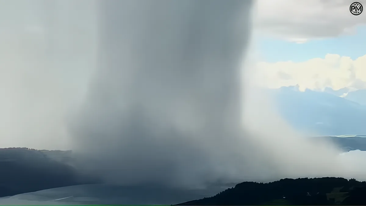 A towering, dense cloud formation dominates the sky, with a mountainous landscape in the background.