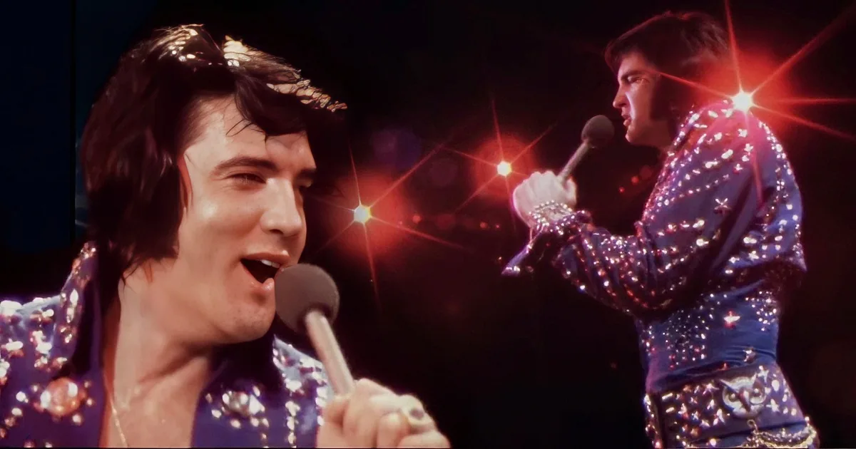 A performer in a glittery blue outfit sings into a microphone on stage with bright lights.