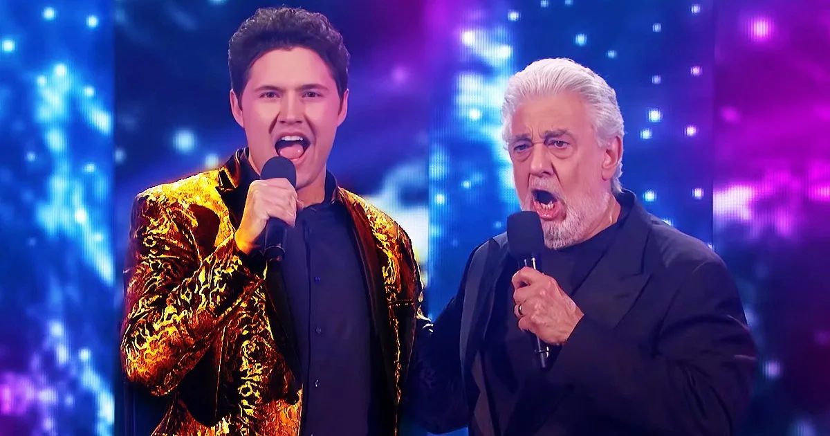 Two men in suits sing passionately on stage with colorful lights behind them.