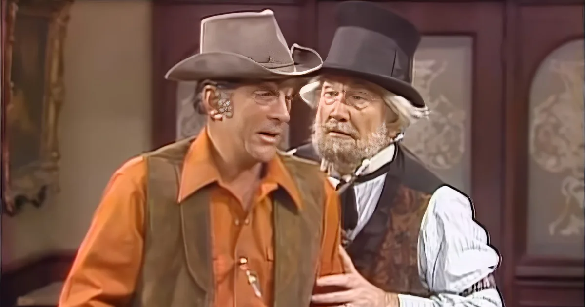 Two men in vintage attire, one in a cowboy hat and the other in a top hat, appear to be in a dramatic or comedic scene.