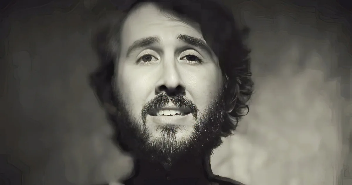 A man with a beard and mustache, looking upward, in a black-and-white image.