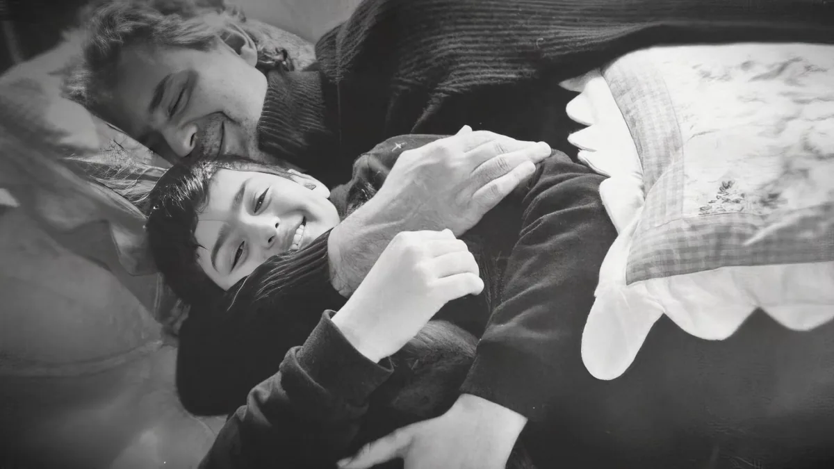 A man and a child are lying in bed, the man holding the child close.