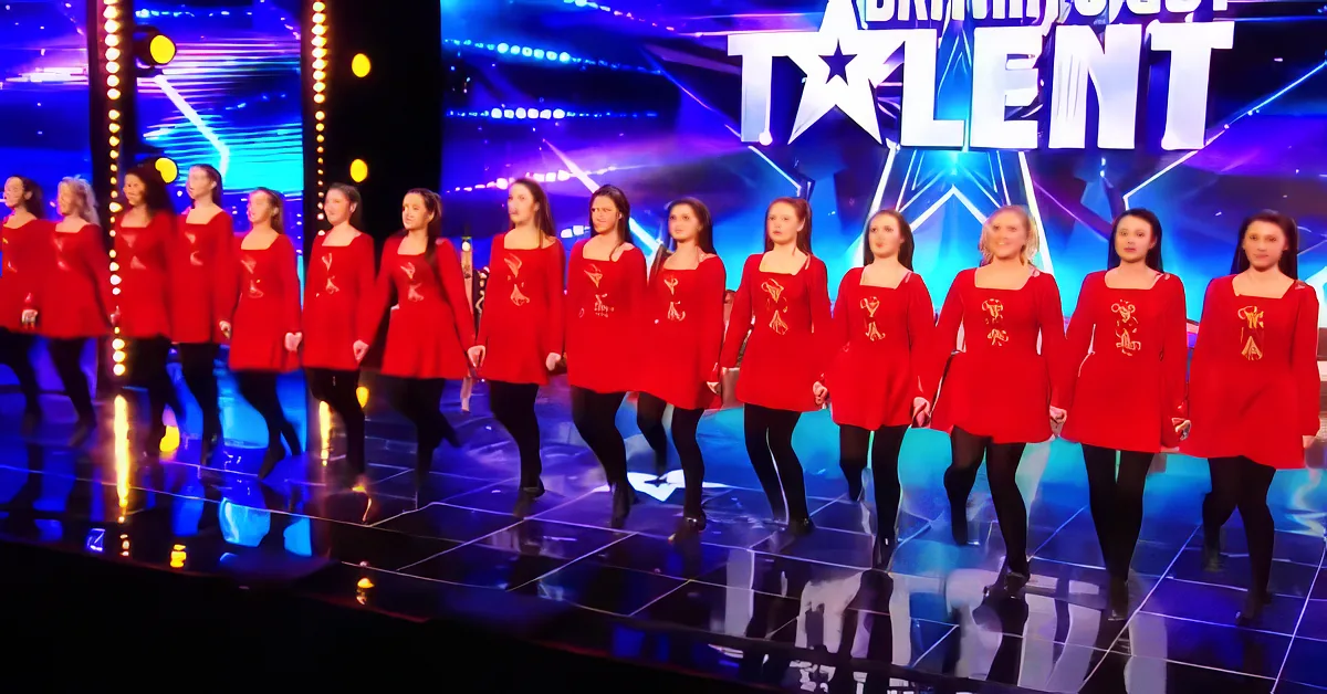 A group of performers in red costumes stands on a stage at "America's Got Talent."