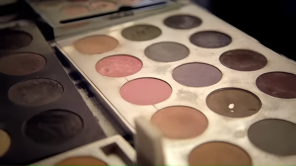A close-up of a makeup palette with various shades of eyeshadow and blushes.