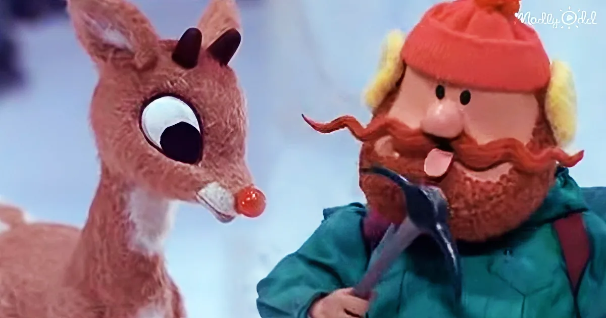 A reindeer with a red nose and a man in a green outfit and red hat are interacting in a snowy scene.