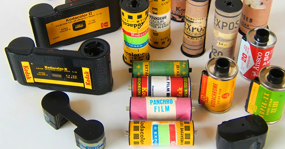 A collection of vintage Kodak film canisters and cameras on a white surface.