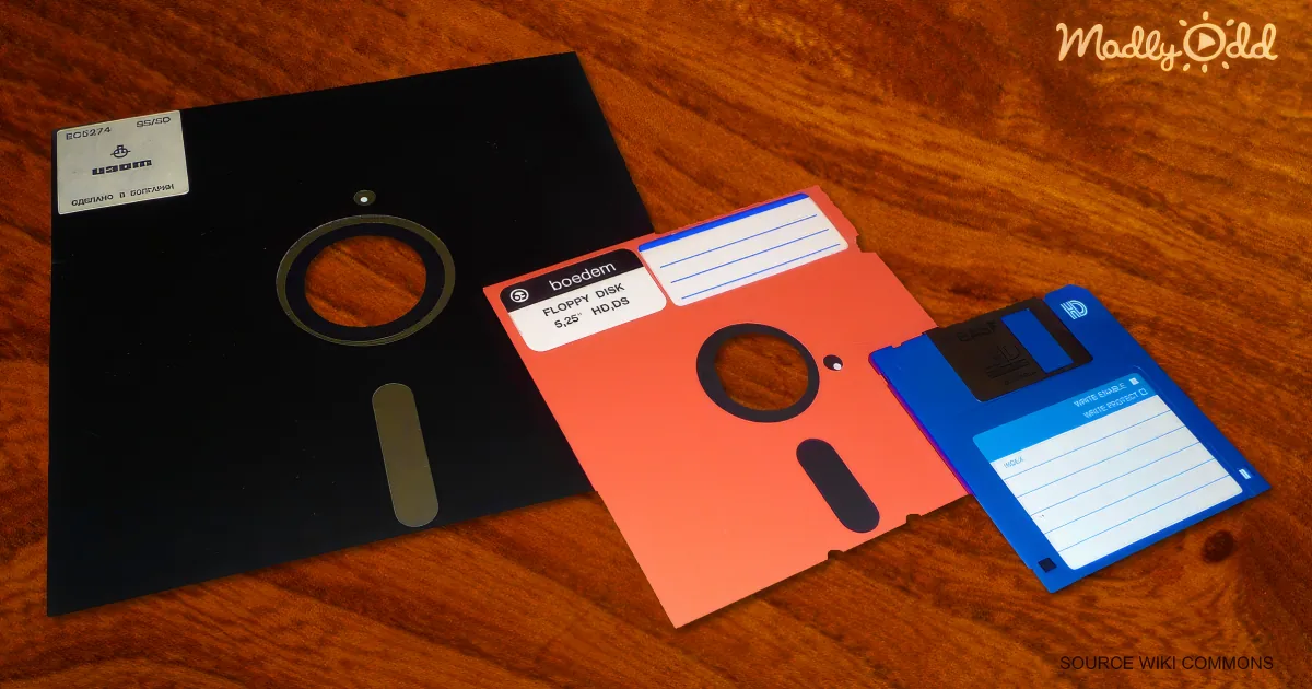 Three floppy disks in black, red, and blue on a wooden surface.
