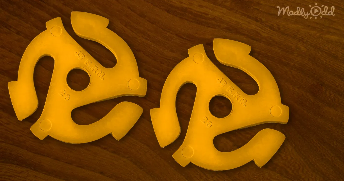 Two yellow plastic 45 RPM record adapters lie on a wooden surface.
