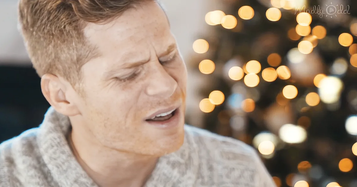 A person in a sweater is crying, with blurred lights in the background.