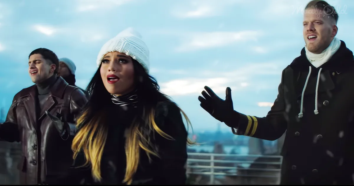 A woman in a white beanie and black coat stands with two men in winter attire, singing against a snowy cityscape backdrop.