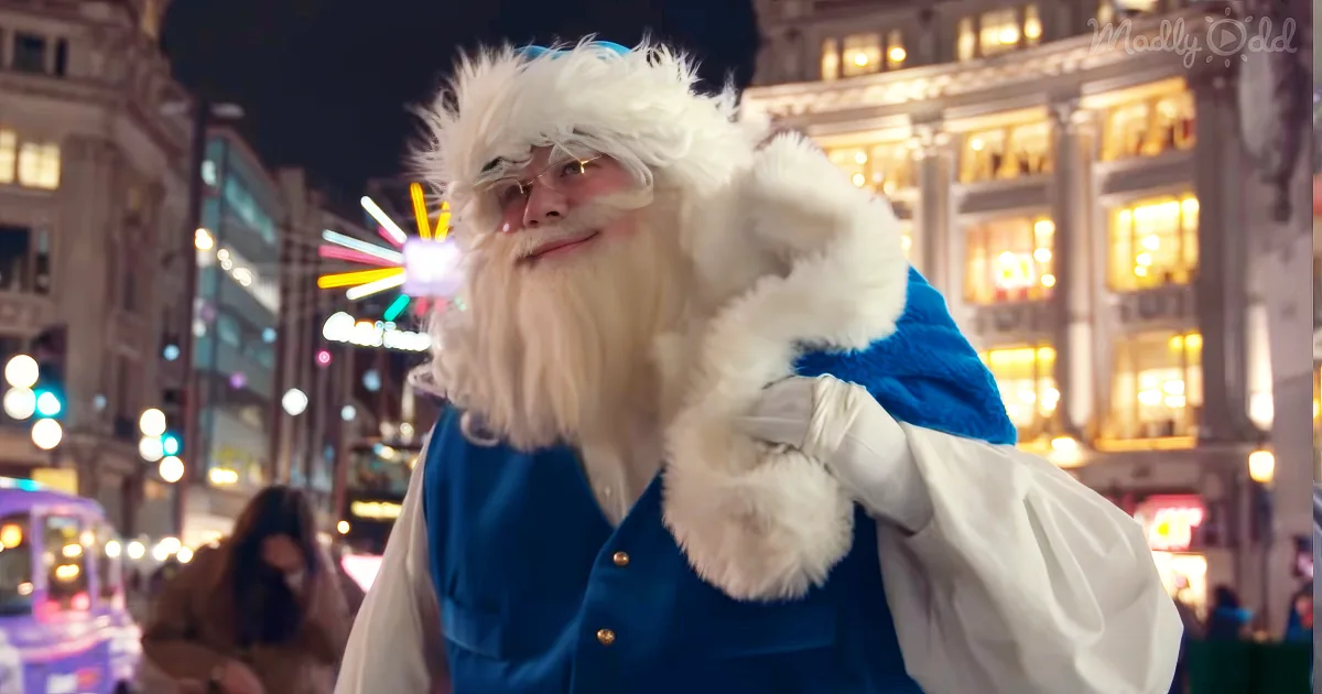 A person dressed as Santa Claus with a white beard and fur hat stands on a busy street at night.