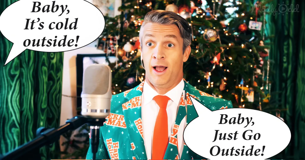 A man in a festive suit sings "Baby, It's cold outside" in front of a decorated Christmas tree.