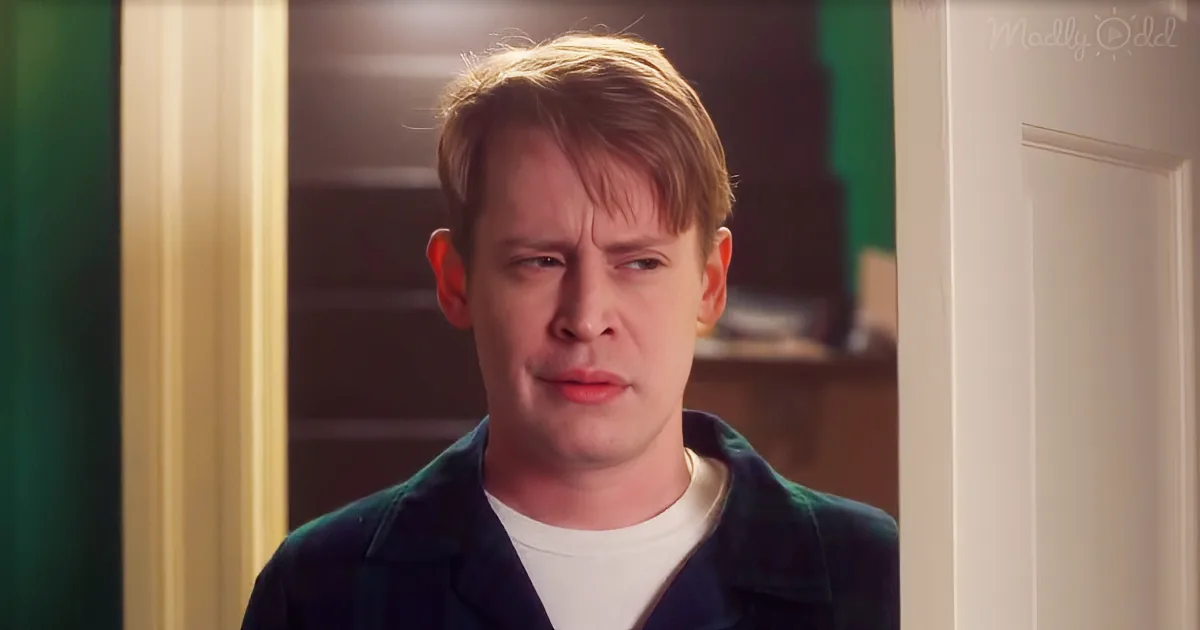 A man with short blonde hair, wearing a dark jacket over a white shirt, looks to the side with a concerned expression.