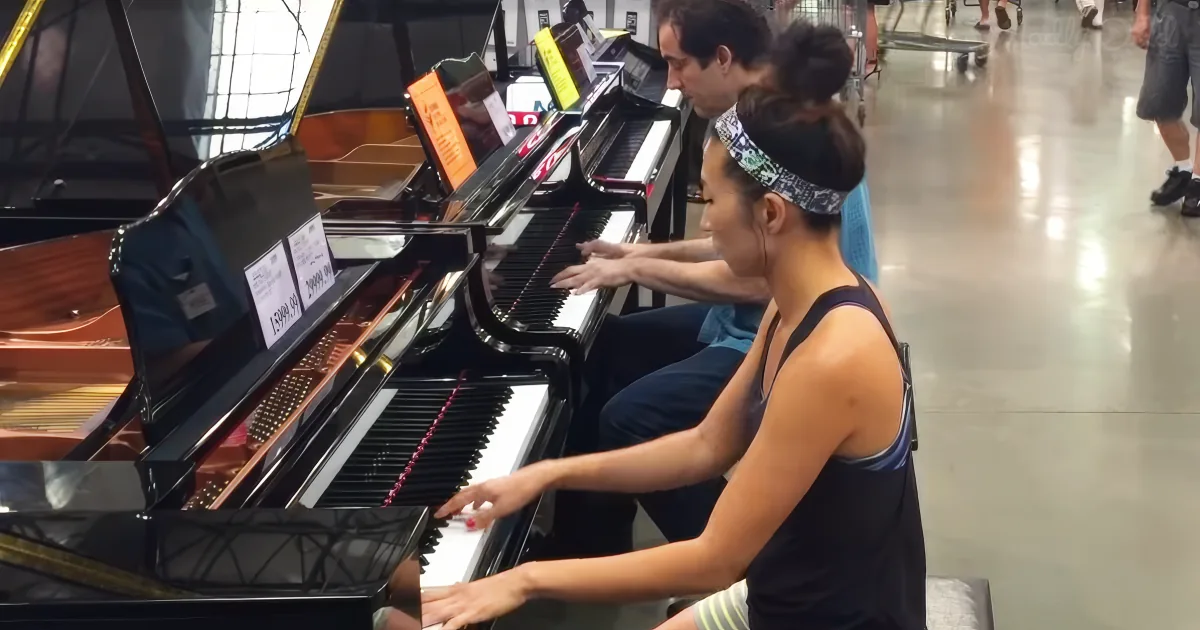 A woman plays a piano in a store, with a man observing her.