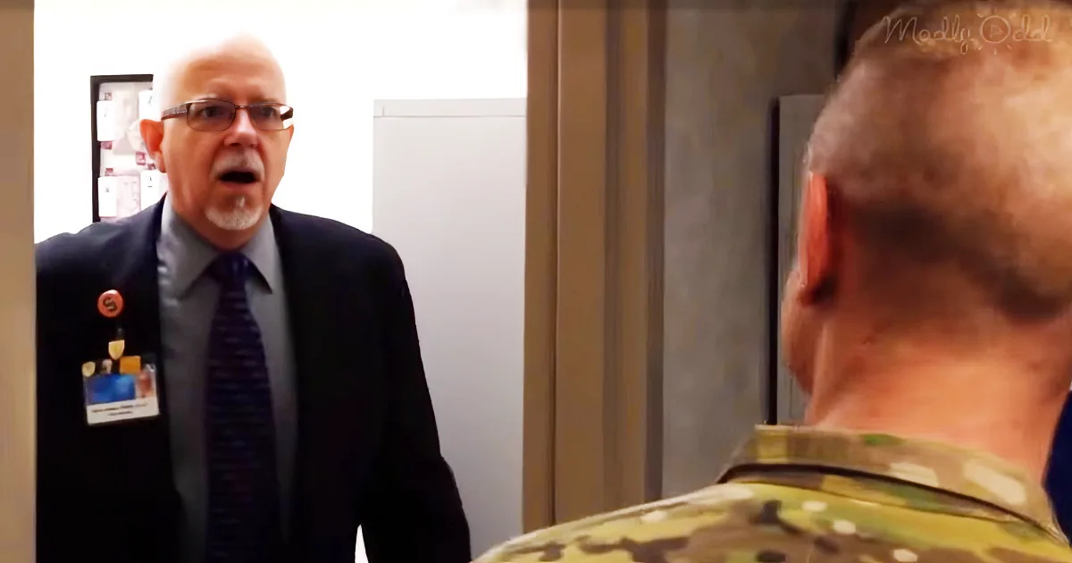 A man in a suit with a name tag and badge is speaking to another man in a camouflage uniform.
