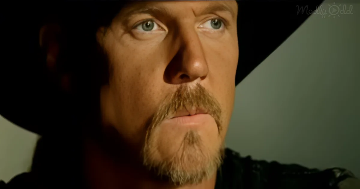 A man with a beard and mustache, wearing a dark hat, looks off to the side with a serious expression.