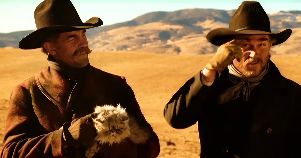 Two cowboys in a desert landscape, one holding a fluffy cat, the other adjusting his hat.