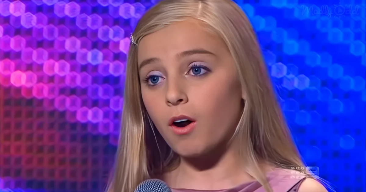 A young girl with blonde hair and blue eyes sings into a microphone against a colorful, bokeh-lit background.