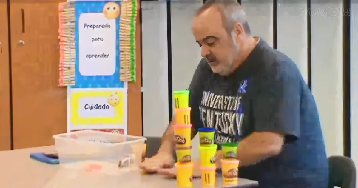 A man in a classroom setting arranges colorful plastic cups on a table.