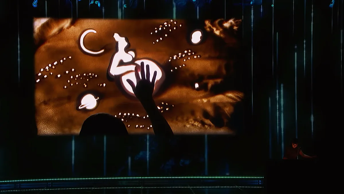 A silhouette of a hand reaching towards a glowing, abstract image of a person on a horse against a dark background.