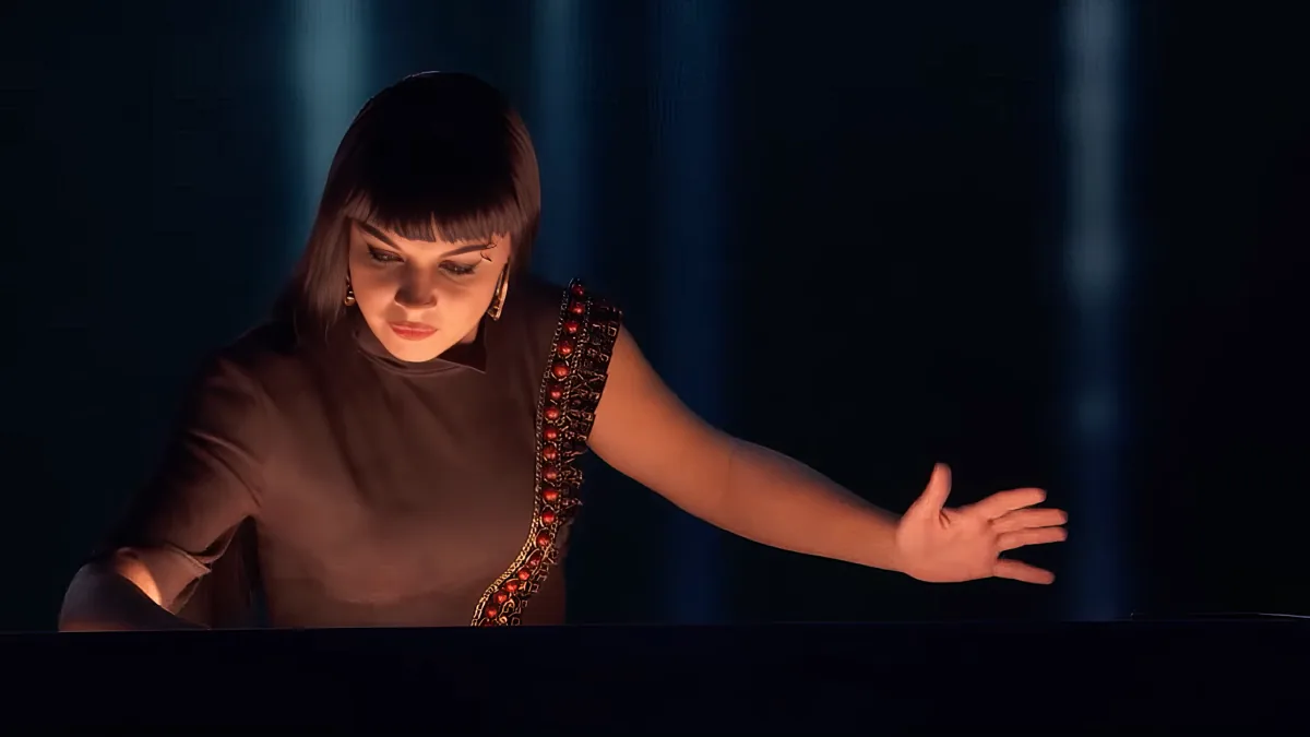 A woman in a brown outfit with red embellishments extends her arms outward in a dark, dramatic setting.