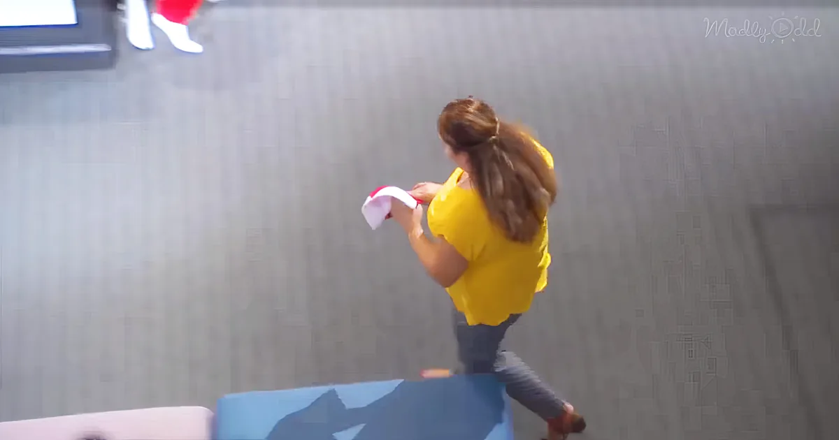 A child in a yellow shirt is holding a red object, standing on a blue surface, with a gray background.