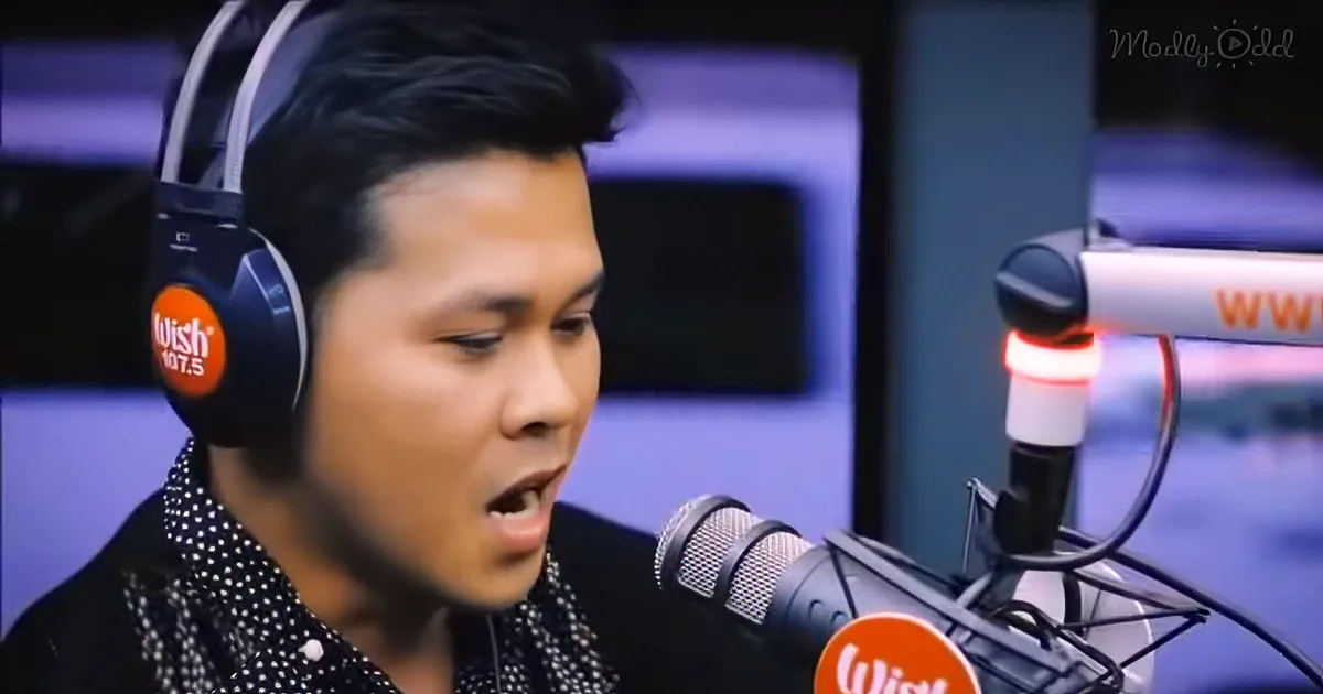 A man wearing headphones sings into a microphone in a studio setting.
