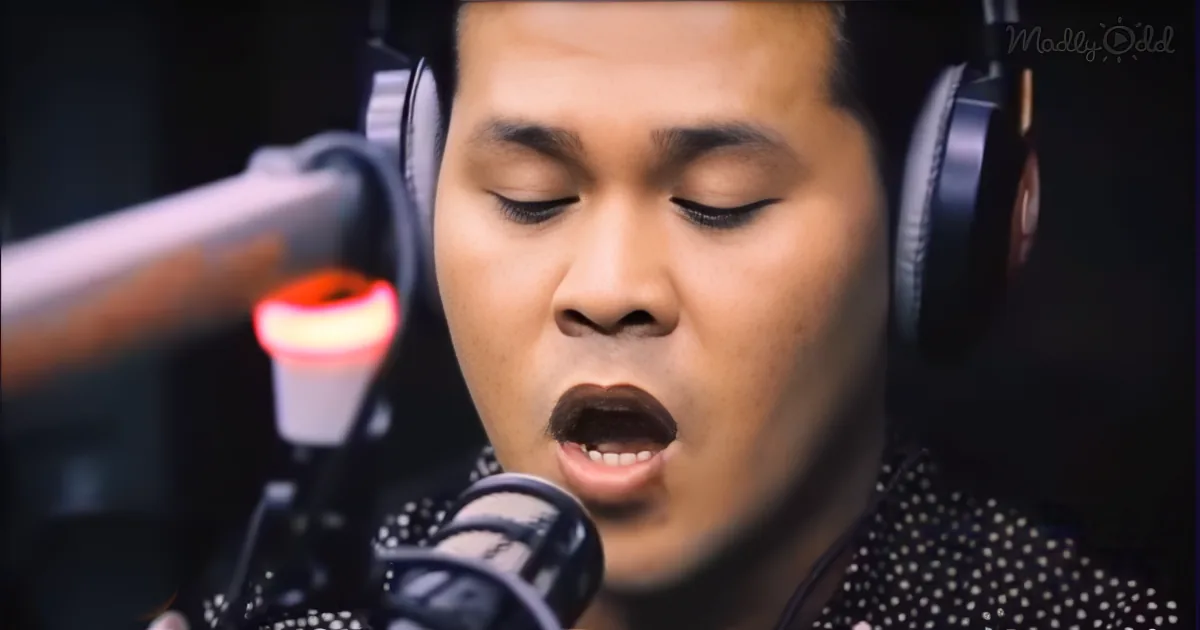 A person wearing headphones sings into a microphone in a recording studio setting.