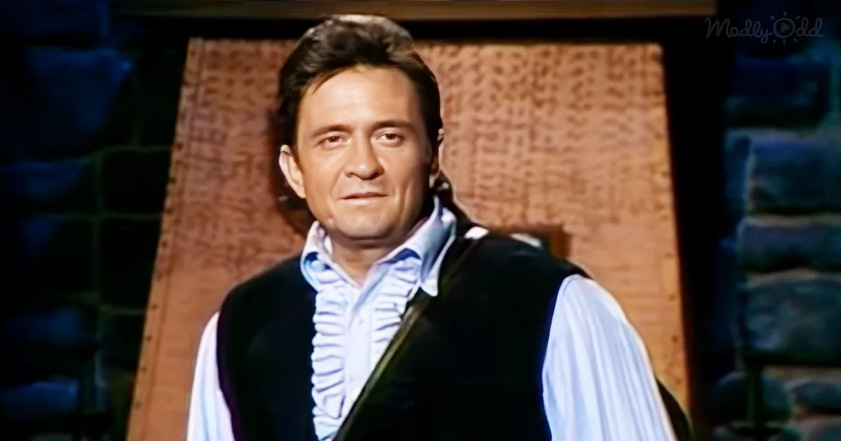 A man with dark hair, wearing a white shirt and black vest, stands in front of a textured background.