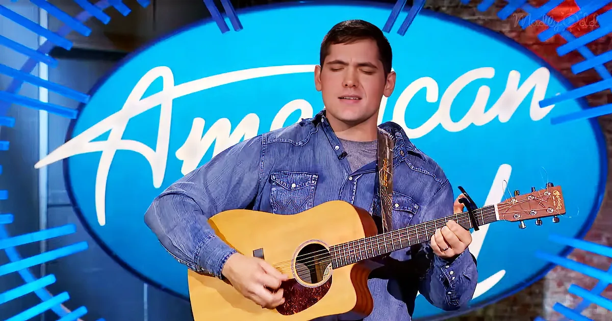 A man in a denim shirt plays an acoustic guitar on stage with an "American" backdrop.
