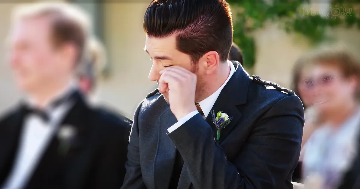 A man in a suit with a boutonniere wipes his eye, surrounded by blurred figures.