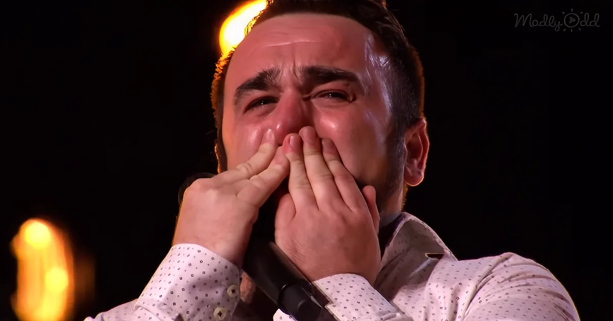 A man in a white polka dot shirt covers his mouth with his hands, appearing emotional.