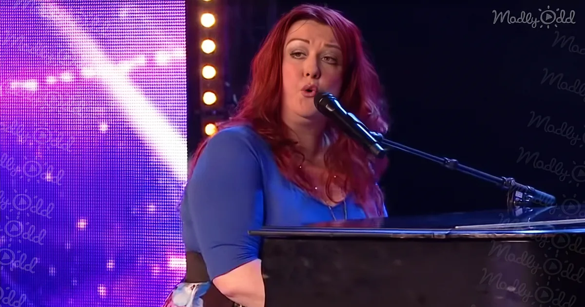 A woman with red hair sings into a microphone while playing a piano on stage.