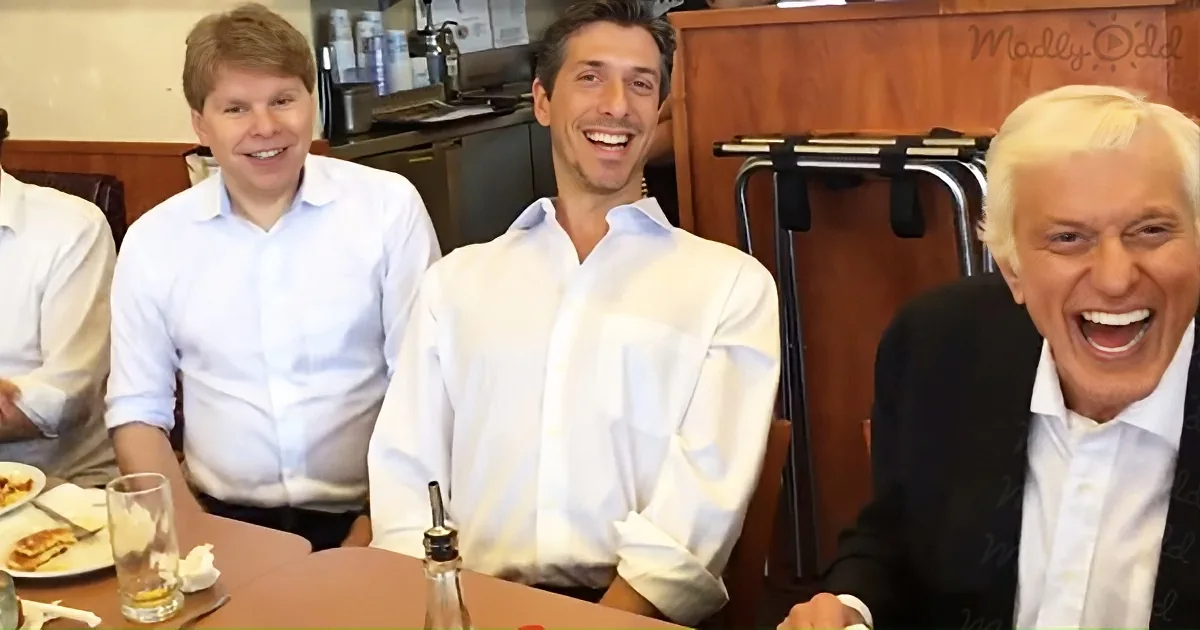 Three men in a restaurant, one laughing, another smiling, and the third appearing surprised.
