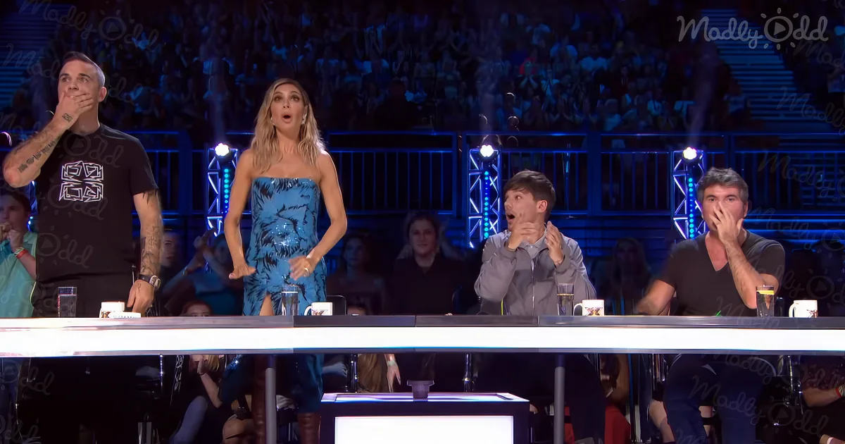 A woman in a blue dress stands on a stage, surrounded by judges reacting with surprise.
