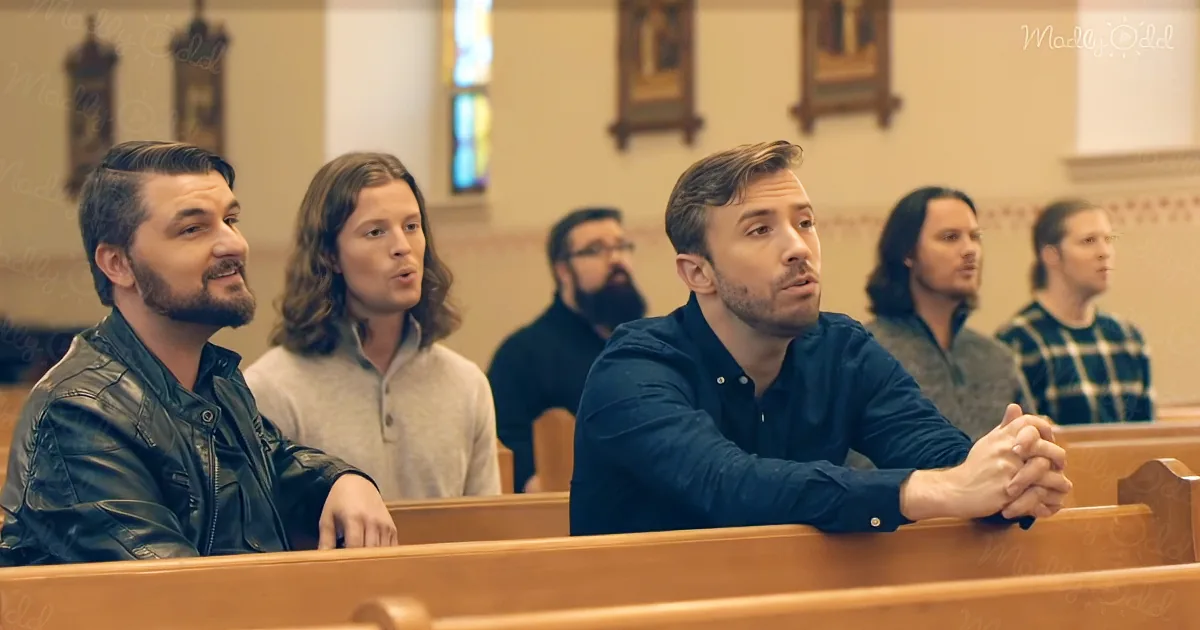A man in a blue shirt sits in a church pew, hands clasped, with others behind him.