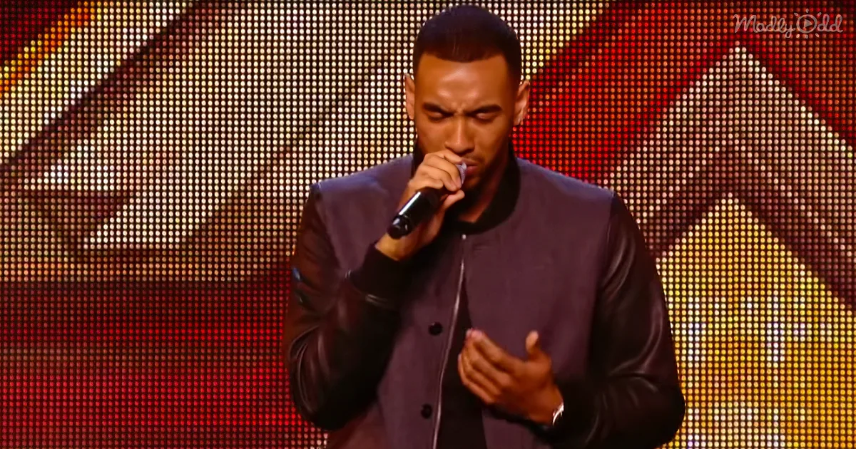 A man in a dark jacket holds a microphone, singing on stage with a colorful LED background.