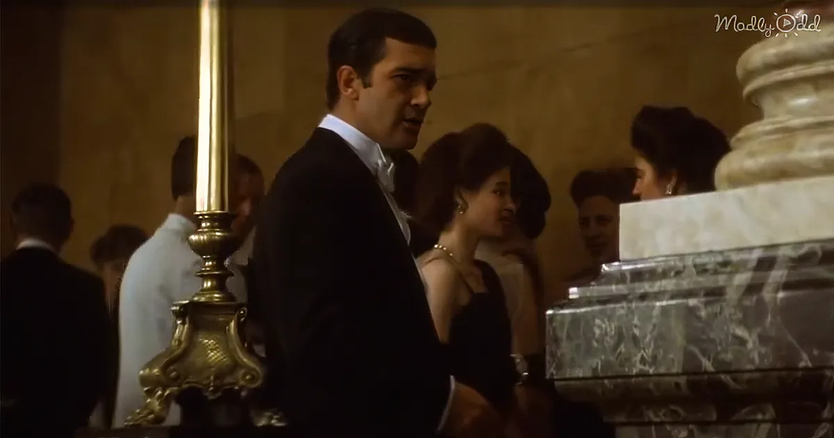 A man in a tuxedo stands beside a woman in a black dress at a formal event.