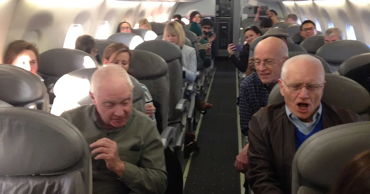 Passengers in an airplane cabin, some appearing to be in discomfort or distress.