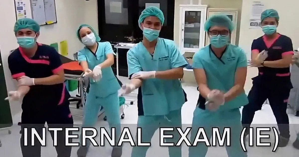 Medical professionals in scrubs and masks perform a synchronized dance in a clinical setting.