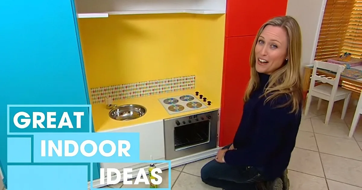 Woman sits near colorful play kitchen with text "Great Indoor Ideas" on screen.