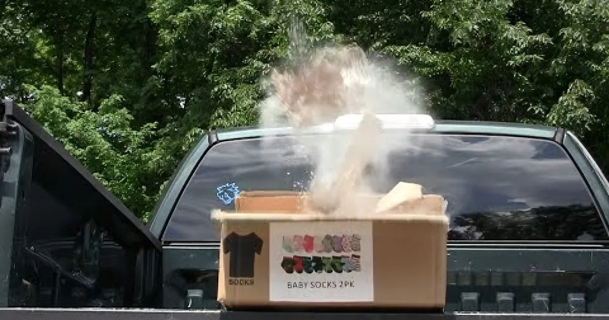 A box of baby socks is being crushed by a truck, sending debris flying.