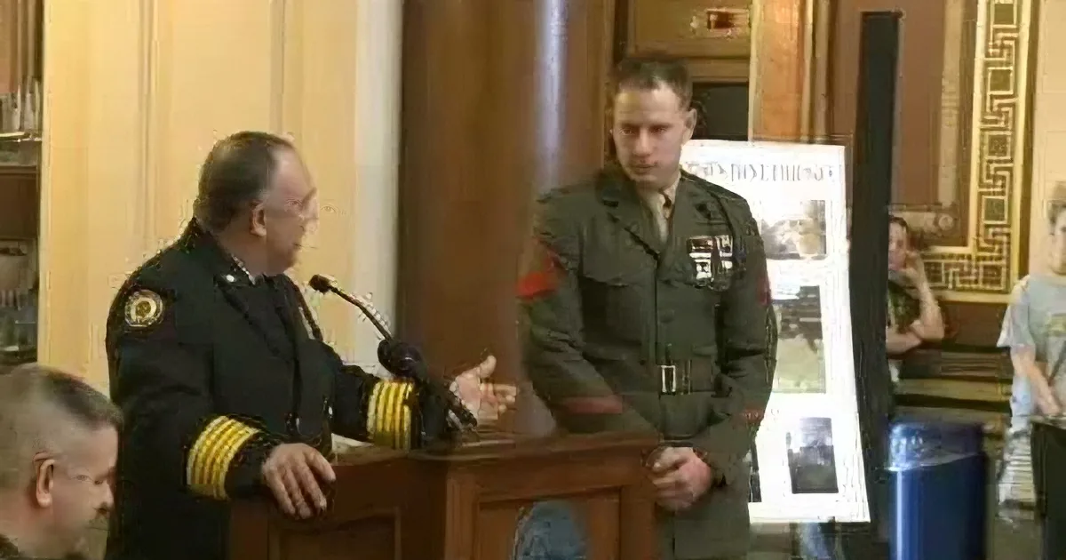 A man in a military uniform stands at a podium, addressing another man in a similar uniform.