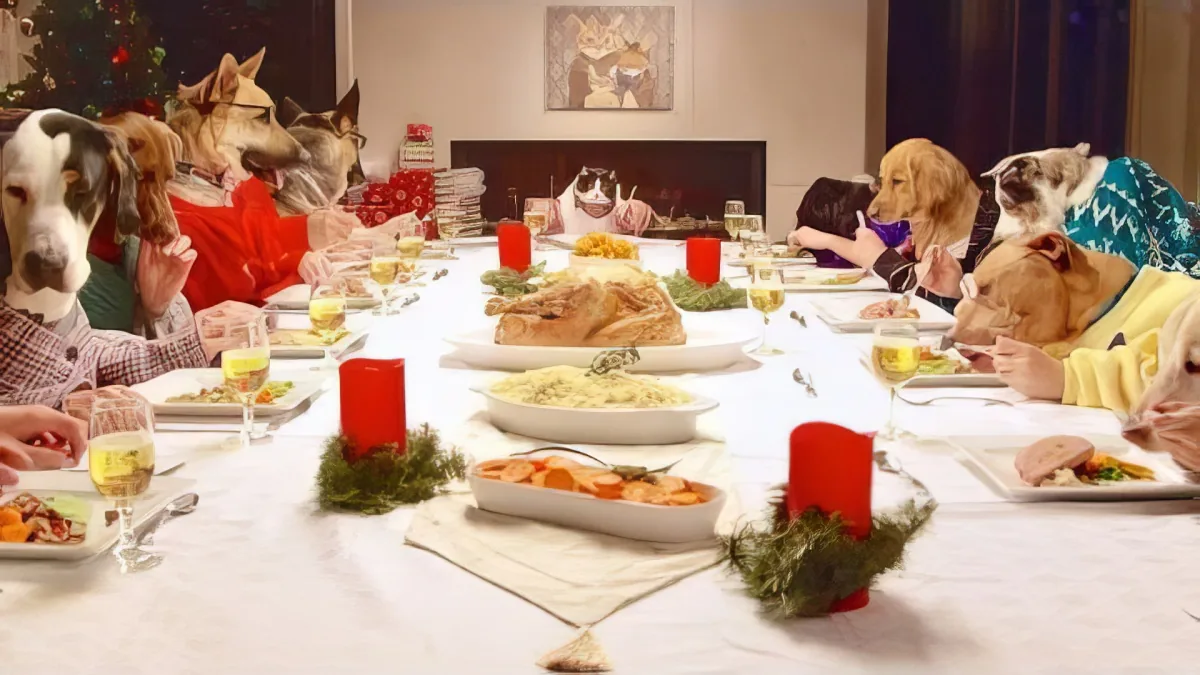Dogs in holiday sweaters sit at a festive table with food and candles.