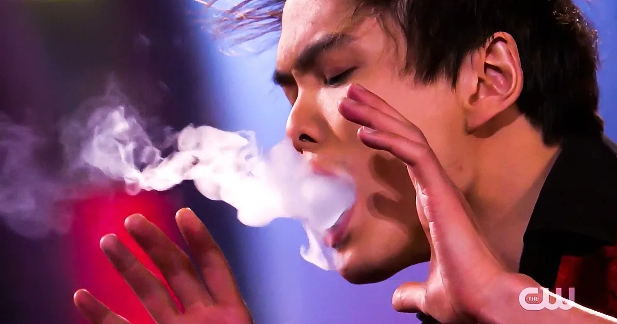 A person blows smoke rings with a red object, creating a dramatic visual effect.