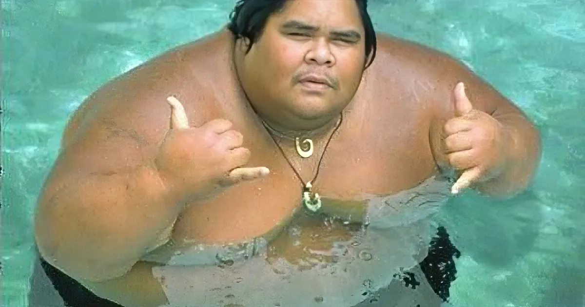 A person in a pool gives two thumbs up while wearing a necklace.