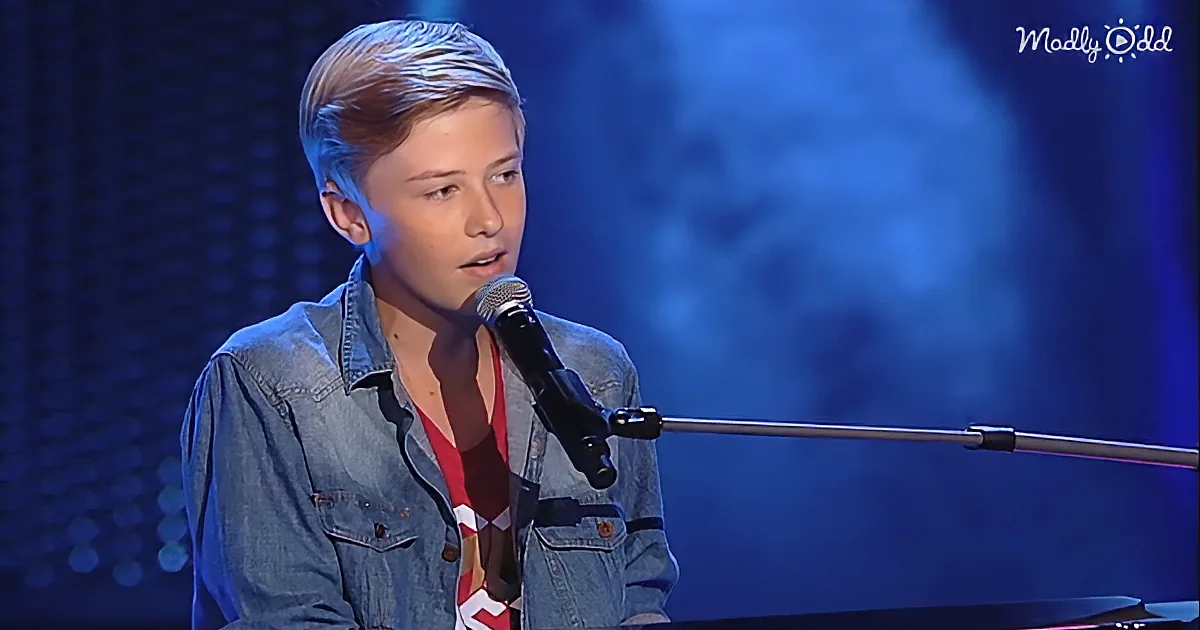 A young person in a denim shirt sings into a microphone on stage.