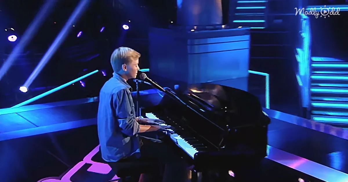 A person plays piano on stage with blue lighting, microphone in front.