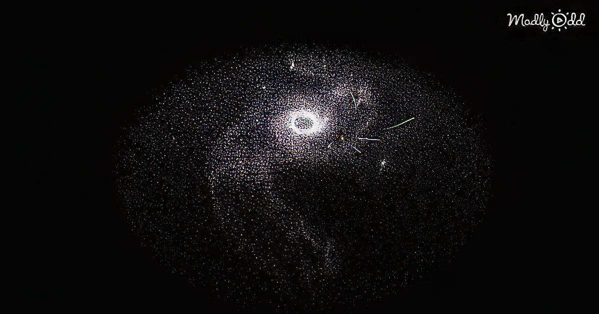 A bright central object surrounded by a dark, speckled halo with colored lines extending outward.
