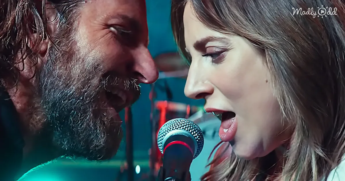 A man and woman are singing into a microphone, their faces close together, in a dimly lit setting.